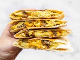 Stacked sausage and egg breakfast quesadillas held close to the camera