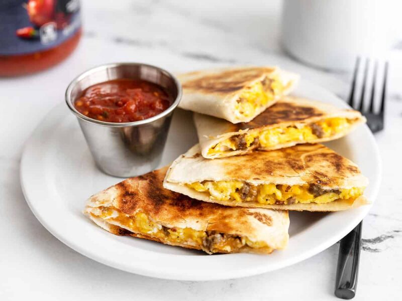 Sausage and egg breakfast quesadillas on a plate with a dipping cup full of salsa