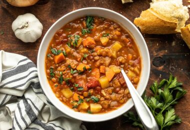 A bowl of tomato lentil sup with bread on the side