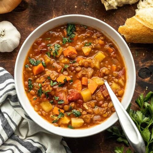 A bowl of tomato lentil sup with bread on the side