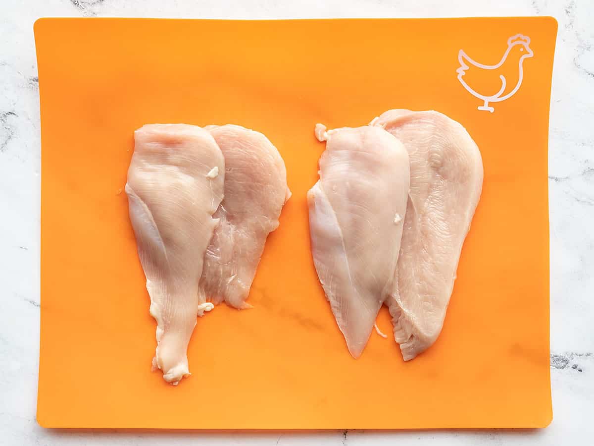Sliced boneless chicken breast on an orange cutting board