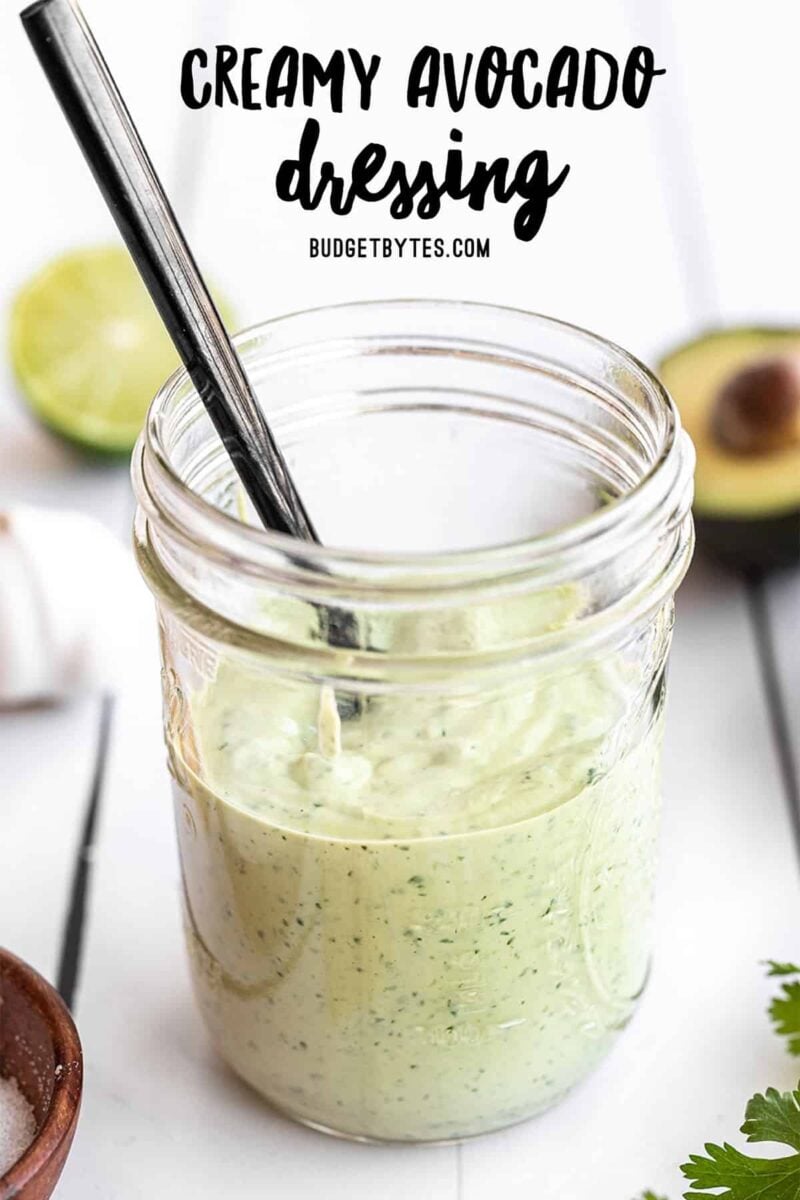 Creamy avocado dressing in a jar with a black spoon, title text at the top