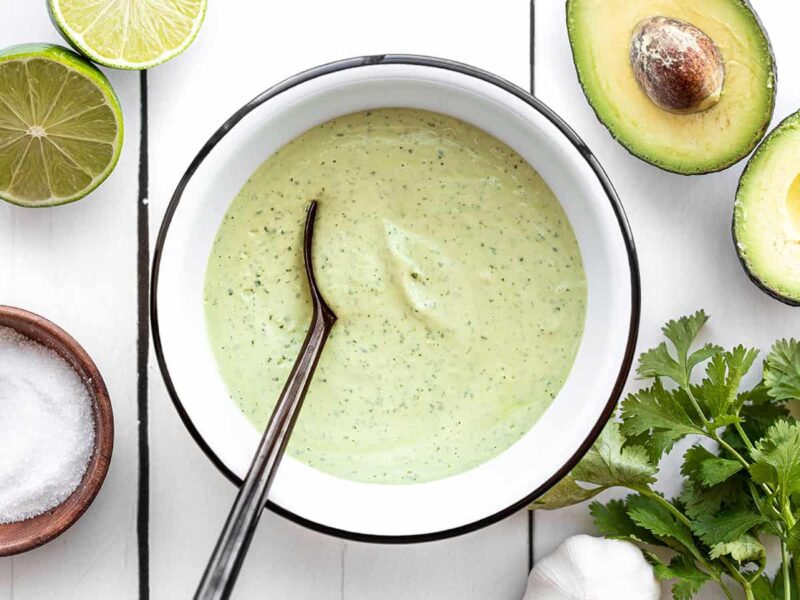 Creamy avocado dressing in a bowl with a black spoon in the center