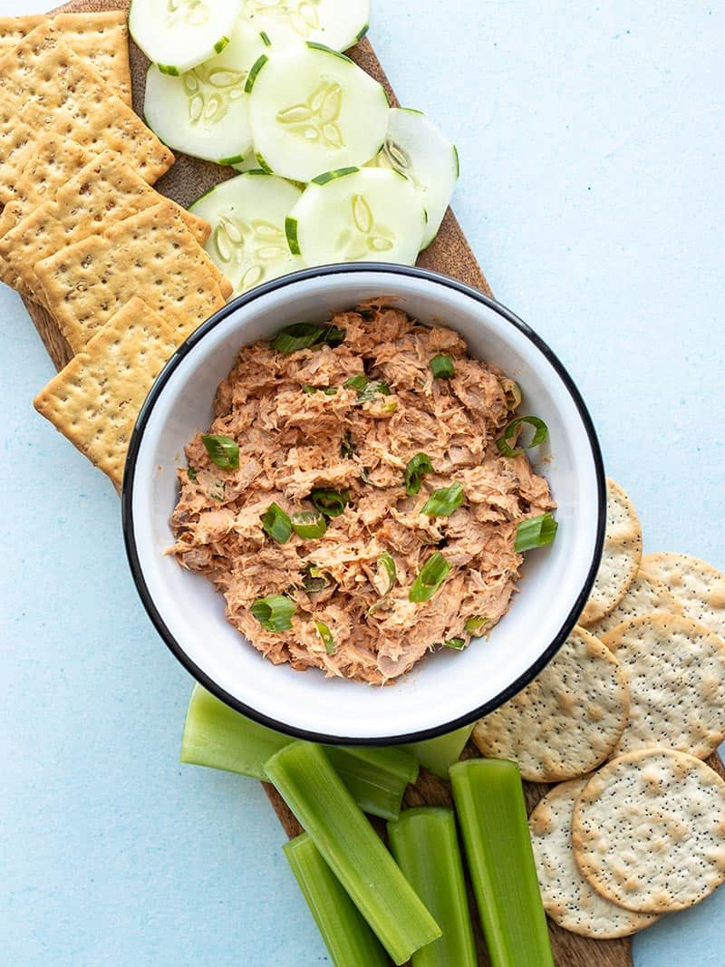 a bowl of gochujang tuna salad on a board with vegetables