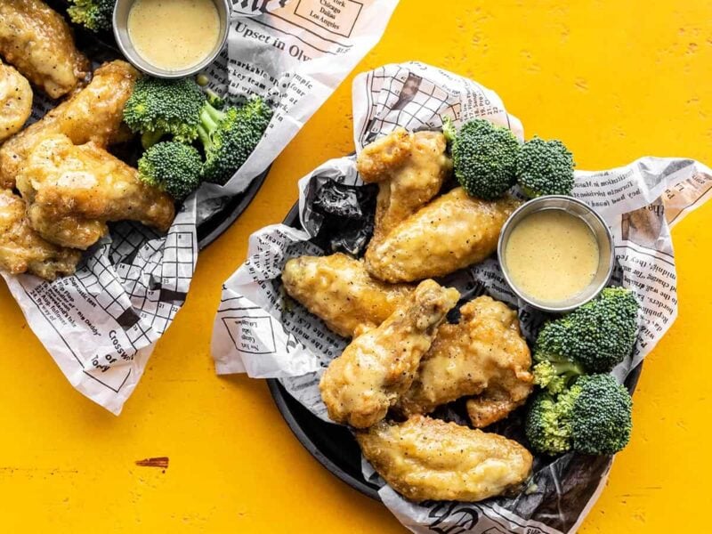 Two trays of honey mustard wings with broccoli and sauce