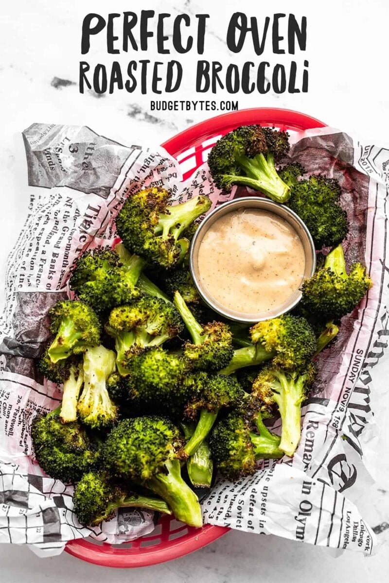 Overhead view of a basket full of oven roasted broccoli with dipping sauce, title text at the top