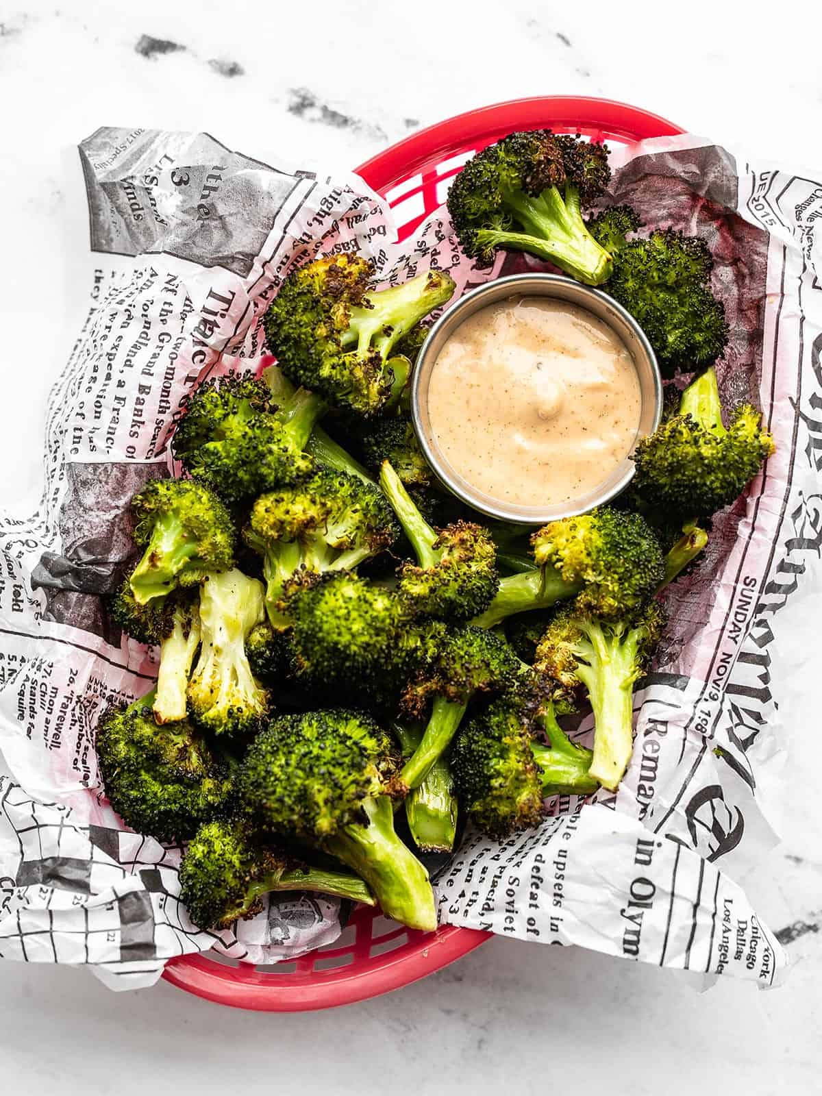 roasted broccoli with comeback sauce in a red plastic basket with paper liner