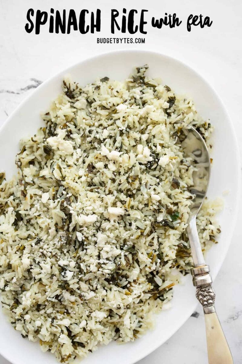 overhead view of spinach rice with feta in an oval serving dish, title text at the top