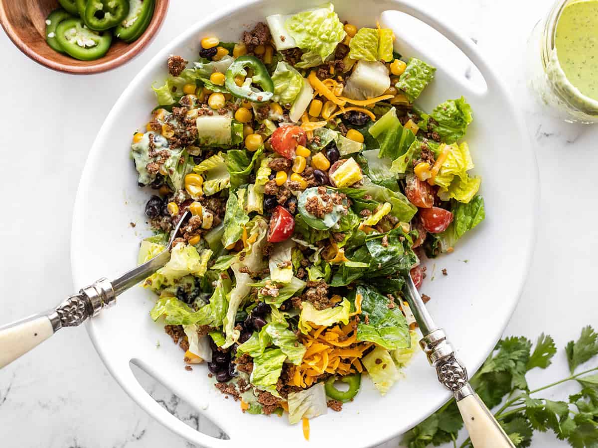 Half-tossed turkey taco salad in a serving bowl with salad tongs