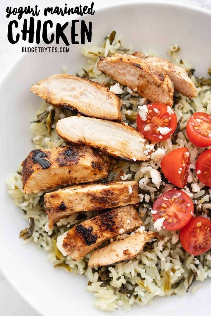 Sliced yogurt marinated chicken on a bed of rice with tomatoes