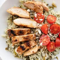 Sliced Yogurt Marinated chicken on a bed of spinach rice with tomatoes and feta