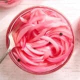 Overhead view of a jar of pickled red onions with a fork.