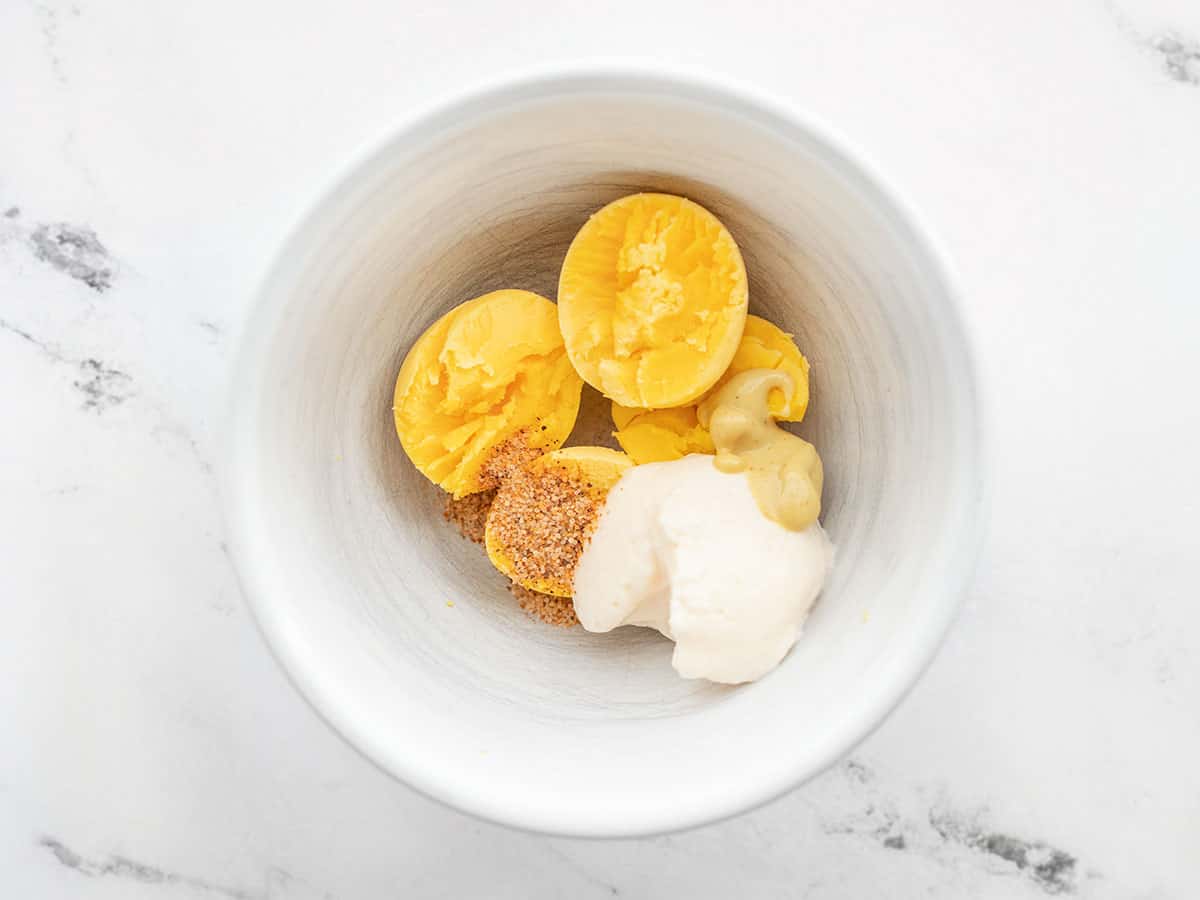 Egg yolks in a bowl with mayonnaise, dijon, and seasoning salt