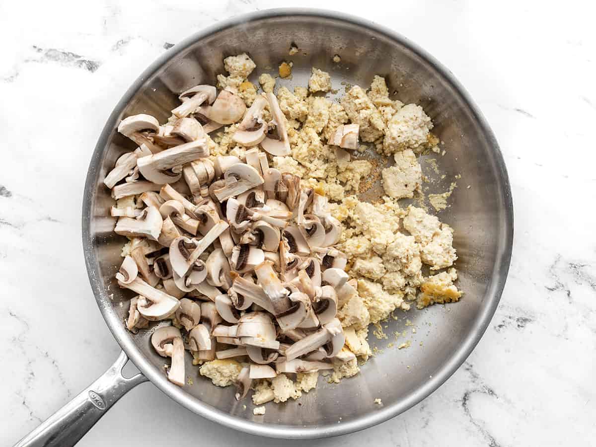 Sliced mushrooms added to the skillet with the tofu