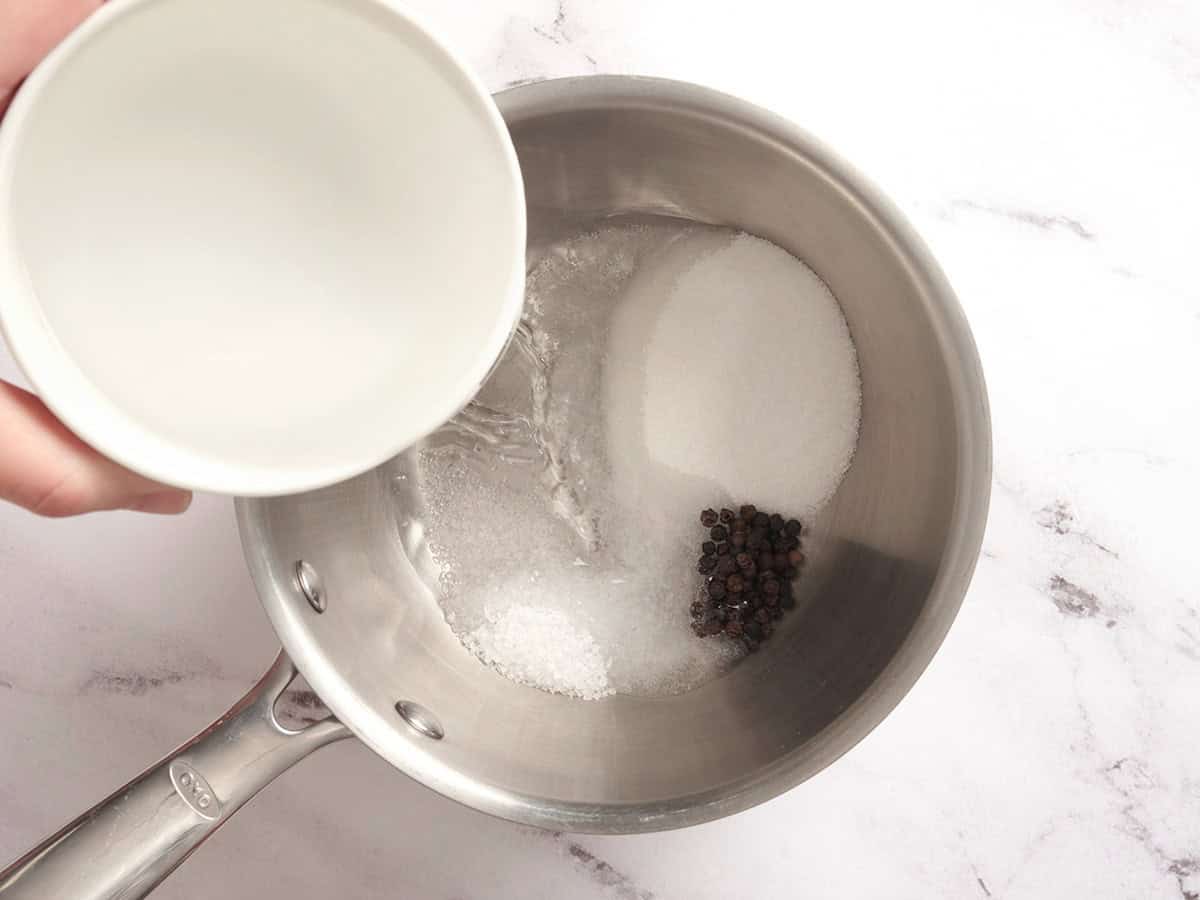 Water being poured into a pot of sugar, salt and peppercorns.