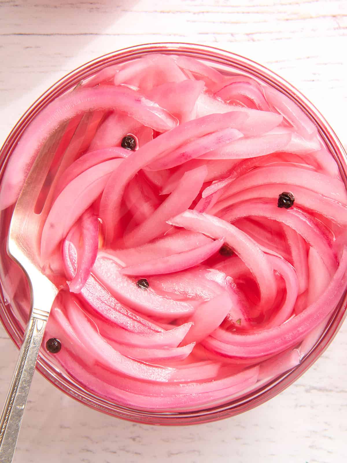 Overhead view of a jar of pickled red onions with a fork.