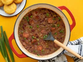 Overhead view of a pot of red beans with corn muffins on the side