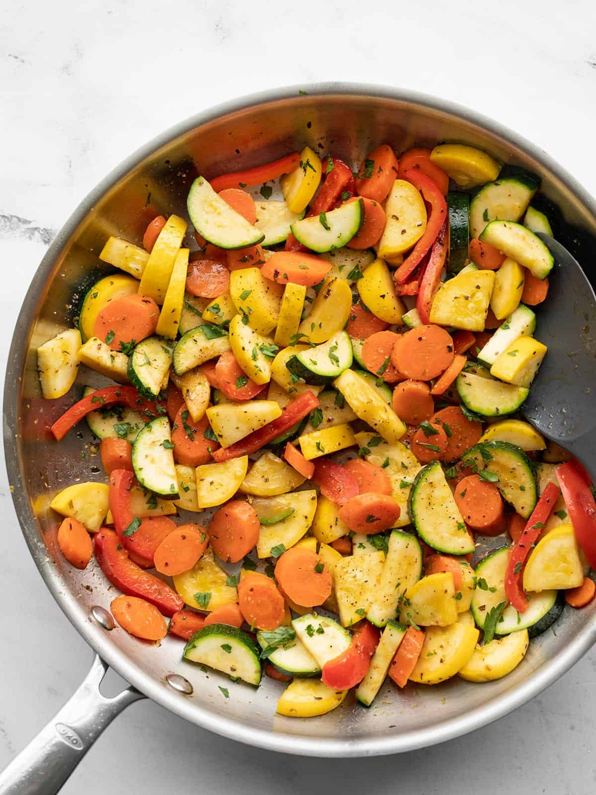 Sautéed vegetables in a skillet with a spatula