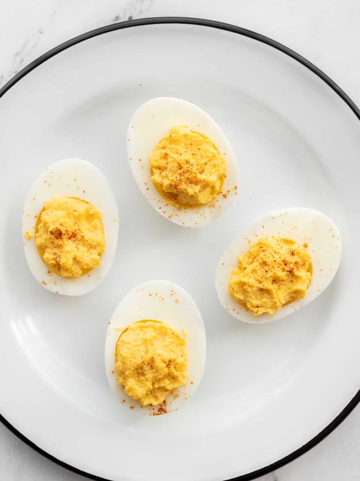 Four deviled egg halves on a white plate