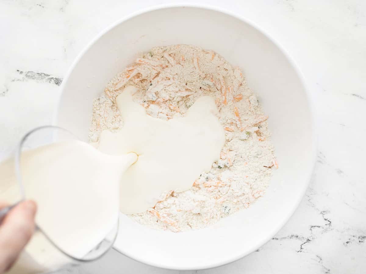 heavy cream being poured into the bowl with the flour mixture