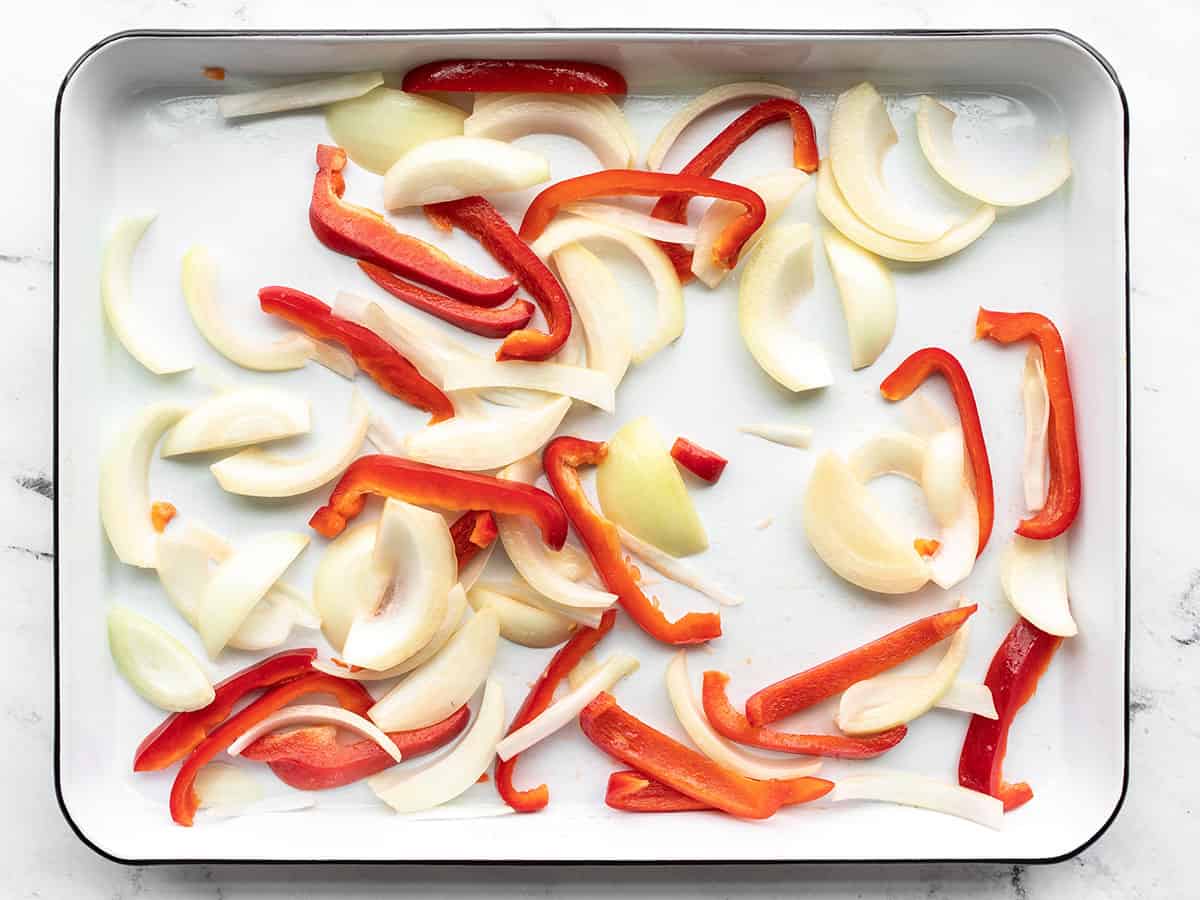 Sliced peppers and onions on a baking sheet