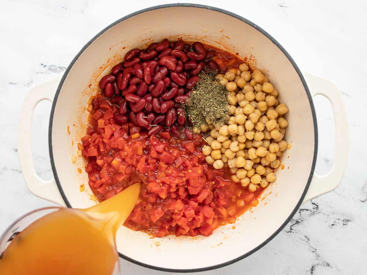 Beans, herbs, tomatoes, and broth added to the soup pot