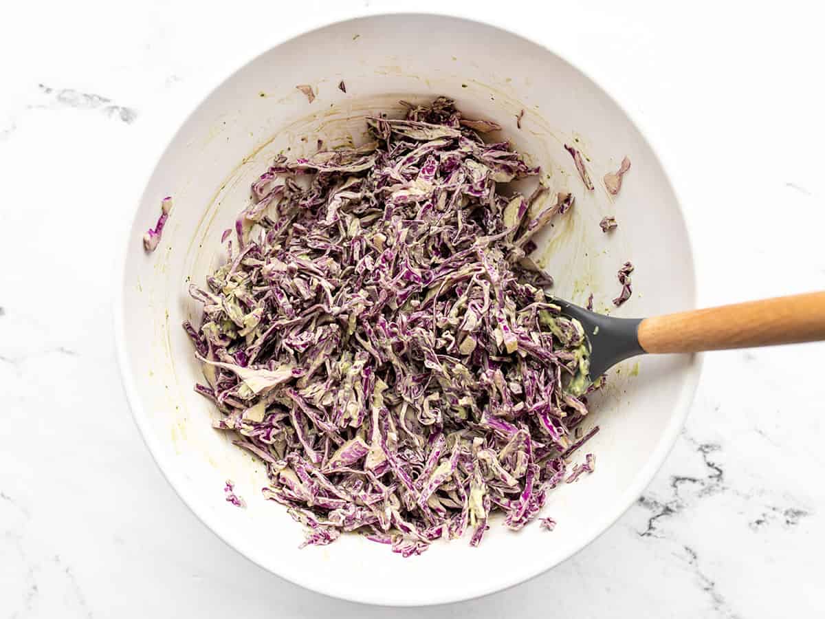 Finished avocado slaw in a bowl with a spatula