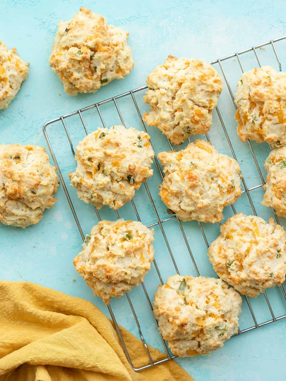 Cheddar drop biscuits on a wire cooling rack, on a blue surface