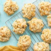 Cheddar drop biscuits on a wire cooling rack against a blue background