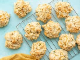 Cheddar drop biscuits on a wire cooling rack against a blue background