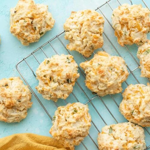 Cheddar drop biscuits on a wire cooling rack against a blue background