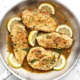 Overhead view of lemon pepper chicken in the skillet with lemon slices