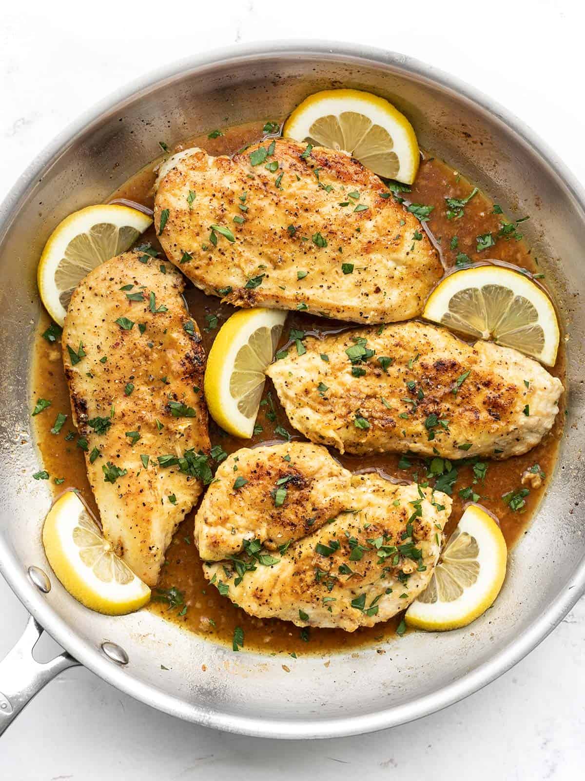 Overhead view of lemon pepper chicken in the skillet, garnished with lemon slices