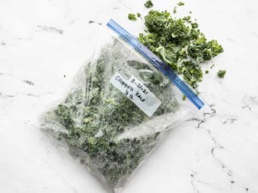 A freezer bag full of kale spilling out onto a marble surface