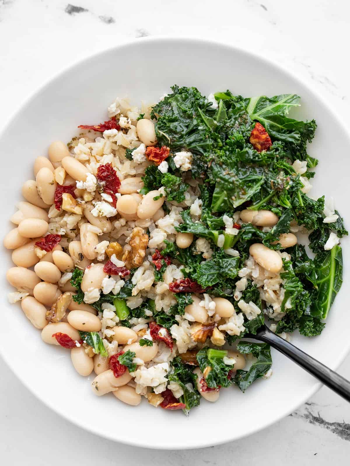 Overhead view of a kale and white bean power bowl with a fork in the side