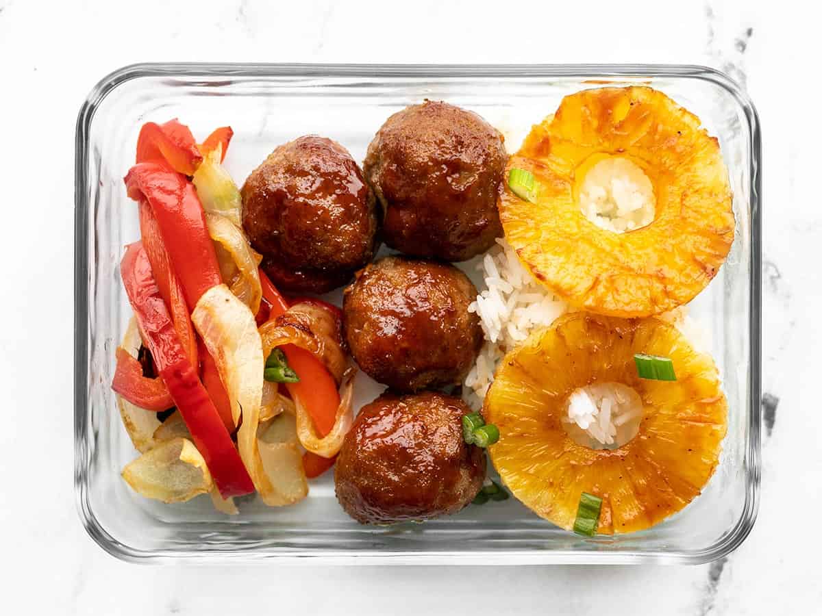 Glass meal prep container with rice, bbq meatballs, peppers, onions, and pineapple