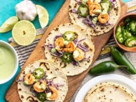 Three Tajín Shrimp Tacos open faced on a wooden board