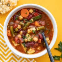 Overhead view of a bowl of vegetarian minestrone with a spoon in the middle