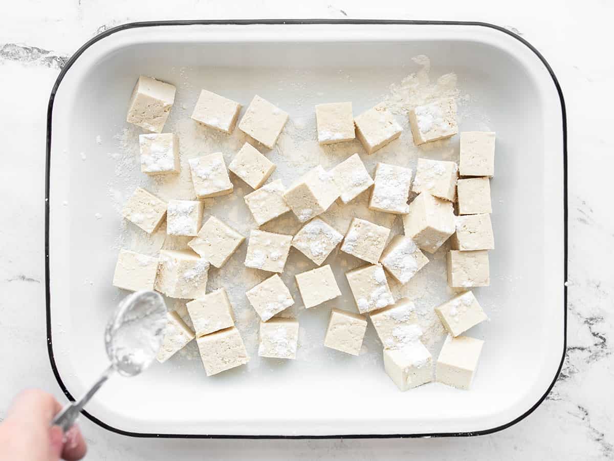 Cubed tofu being sprinkled with cornstarch
