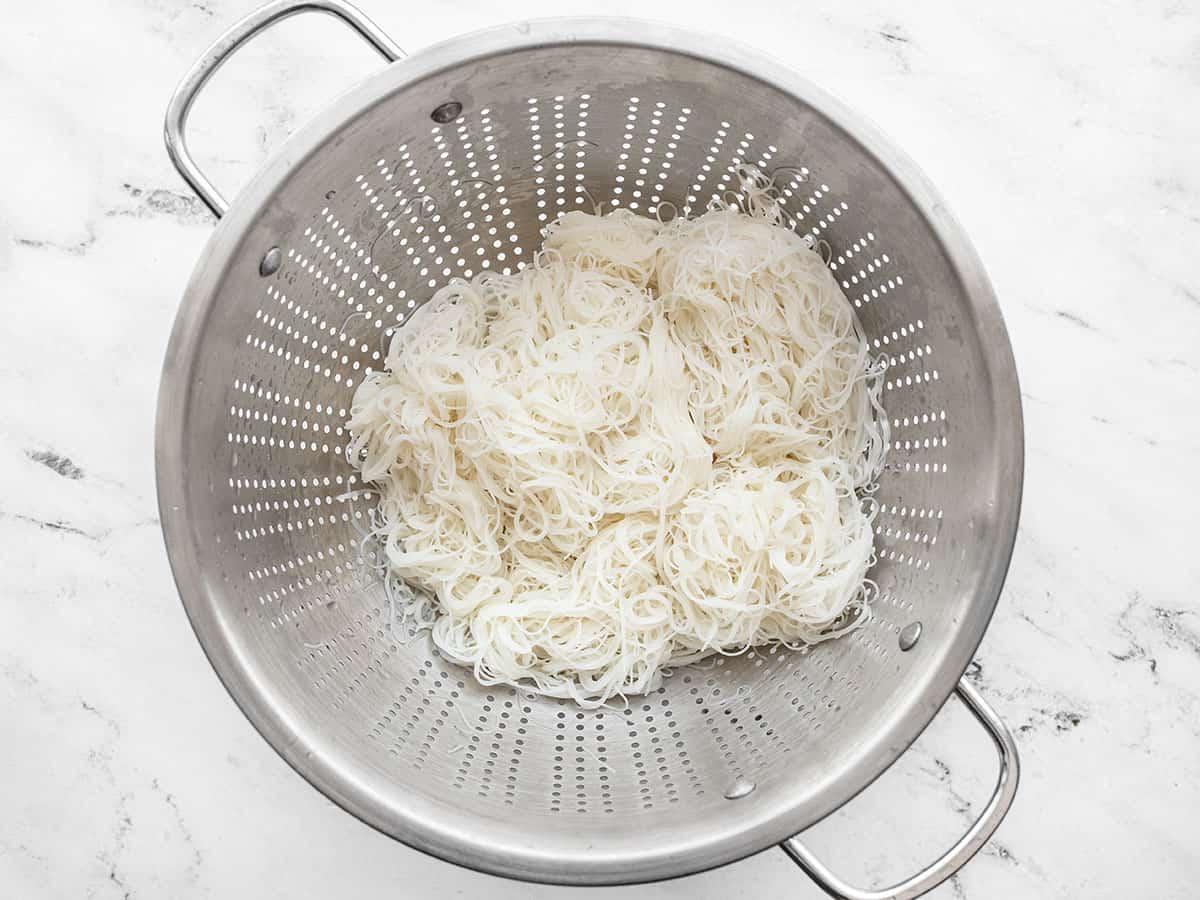 Cooked rice noodles draining in a colander