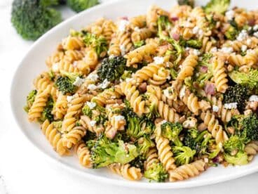 Close up side view of broccoli pasta salad with tomato vinaigrette on a platter