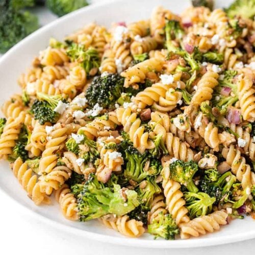 Close up side view of broccoli pasta salad with tomato vinaigrette on a platter