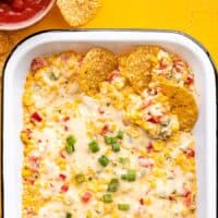 Overhead view of several chips dipped into a dish full of hot corn dip