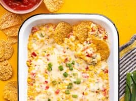 Overhead view of several chips dipped into a dish full of hot corn dip