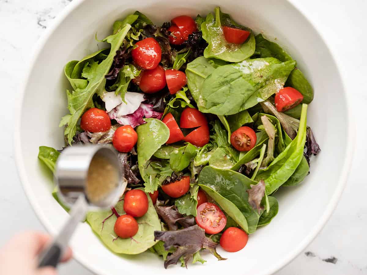 Dressing being poured over the side salad