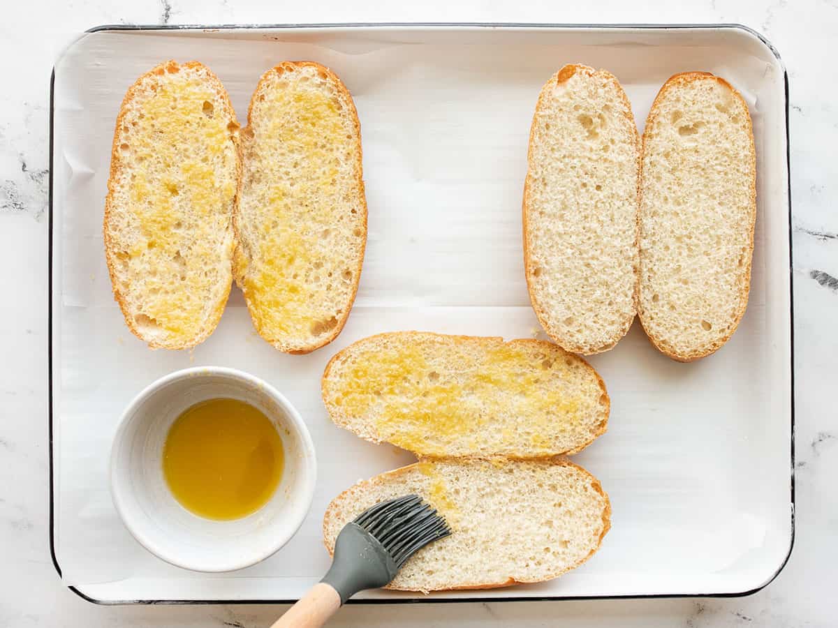 Garlic butter and oil being brushed onto rolls