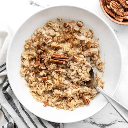 Overhead view of a bowl full of cinnamon pecan cauli oats with a spoon in the center