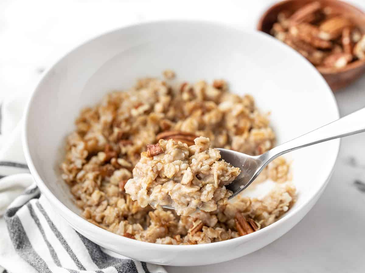 Side view of a spoon lifting a bite of cinnamon pecan cauli oats out of the bowl