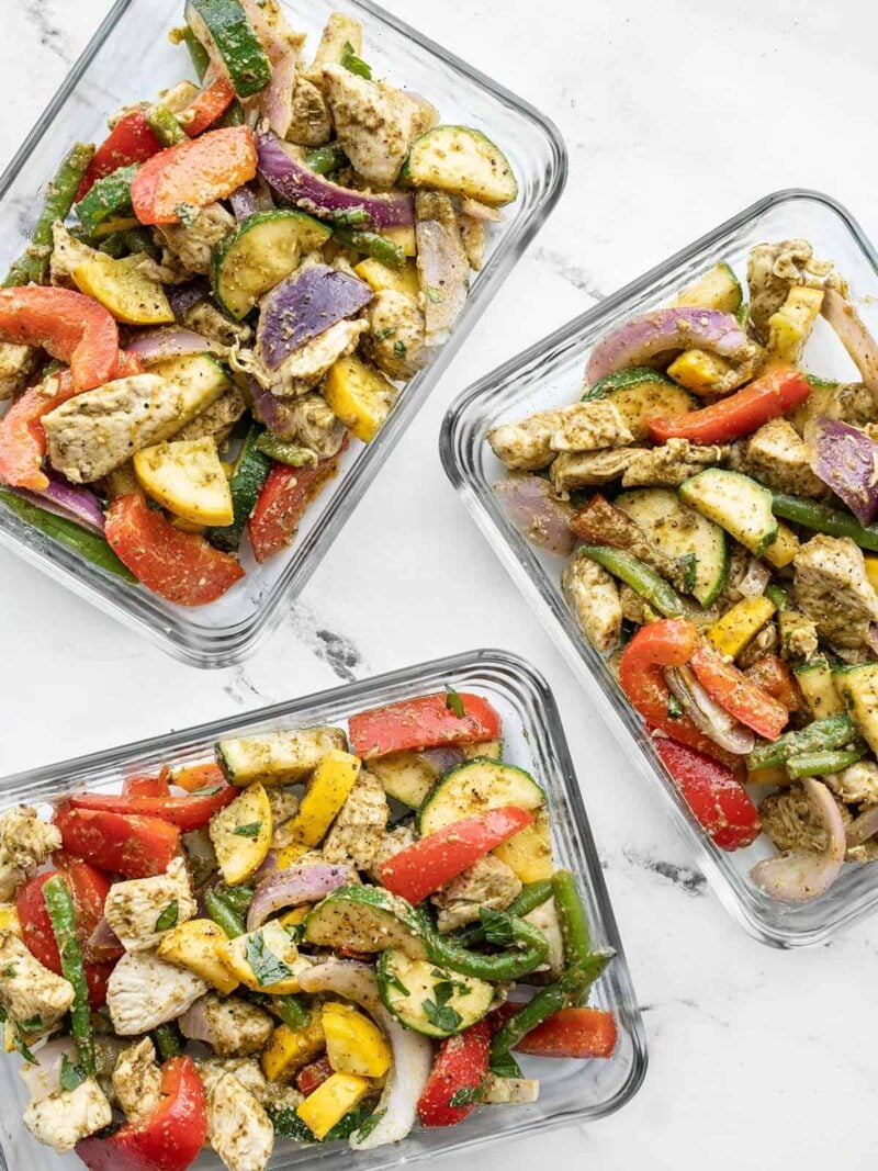 Three glass meal prep containers full of pesto chicken and vegetables