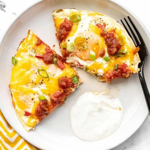 Southwest tortilla baked eggs on a plate with sour cream and a fork
